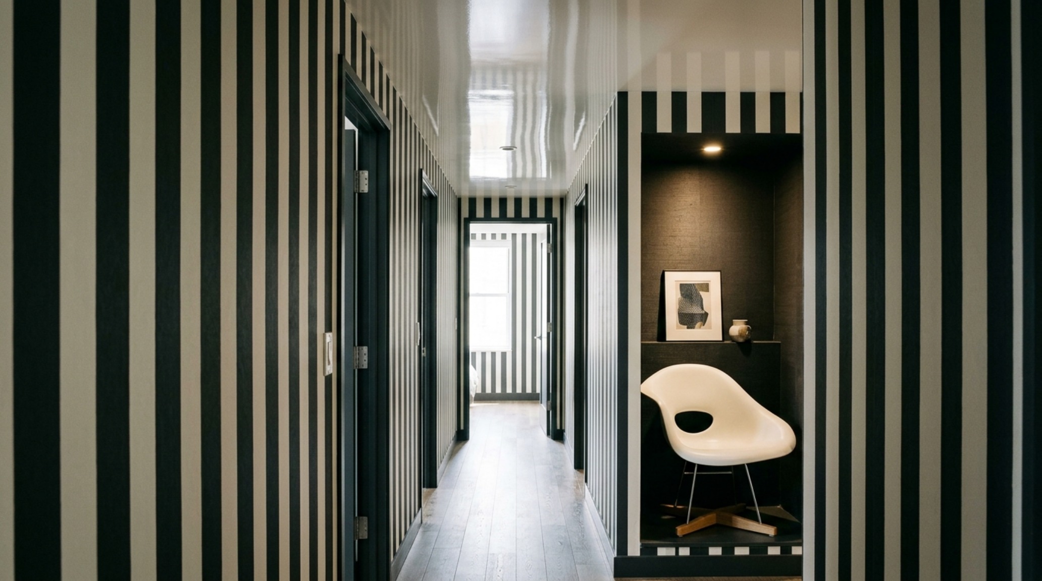 A sophisticated hallway featuring Benjamin Moore Swiss Coffee paint on the ceiling and a high-contrast vertical stripe wallpaper.