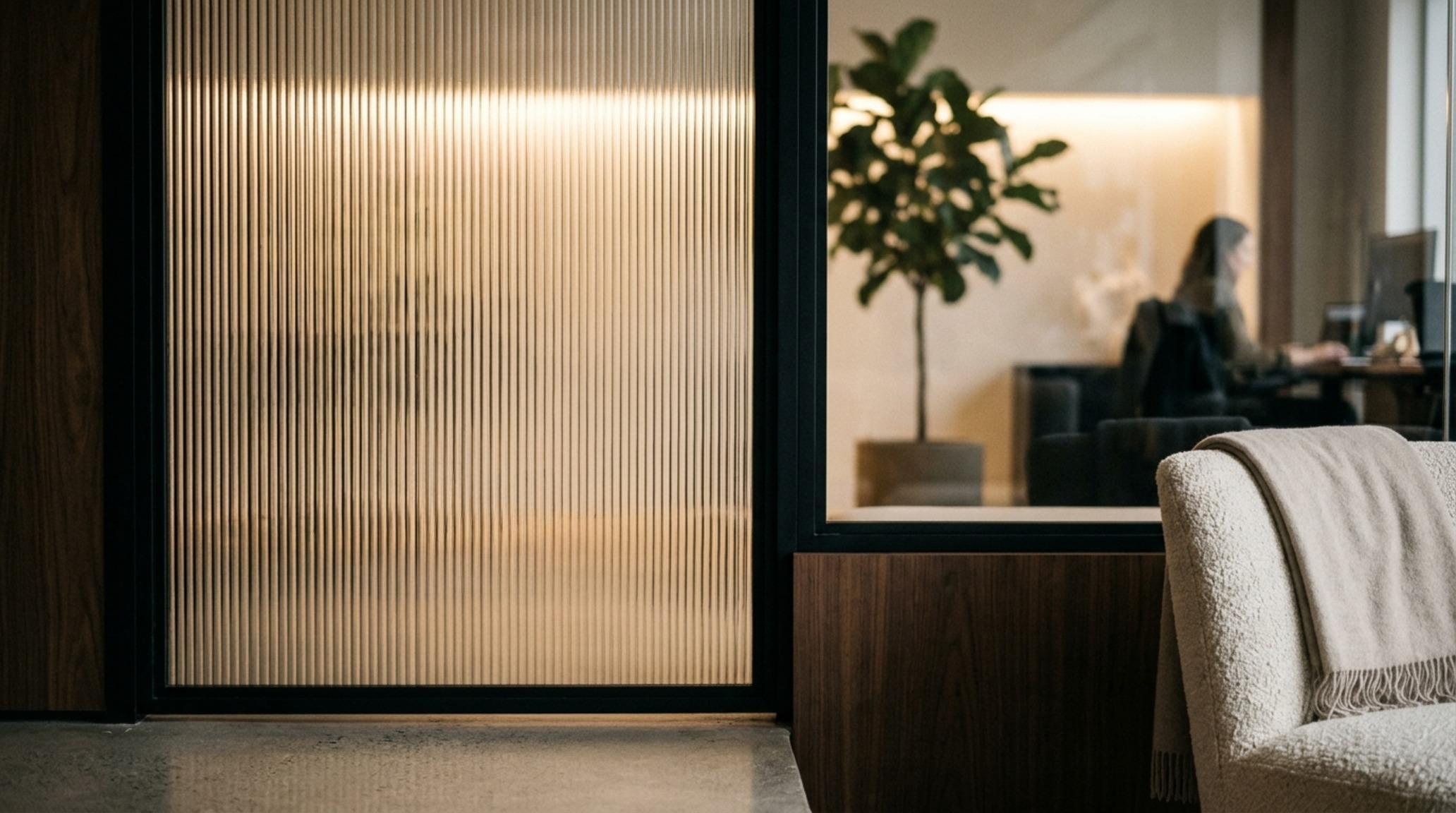 luxury trendy office decor textures focusing on a fluted glass cabinet door reflecting warm 2700K architectural pin-lights