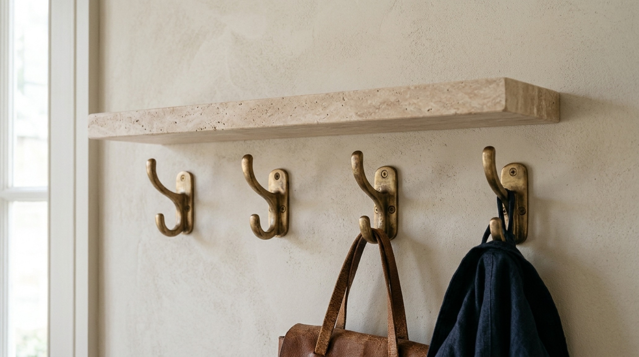 luxury wall mounted coat rack plans textures highlighting the contrast between a honed travertine shelf and hand-patinated unlacquered brass hooks on a plaster-finished wall luxury wall mounted coat rack plans textures highlighting the contrast between a honed travertine shelf and hand-patinated unlacquered brass hooks on a plaster-finished wall