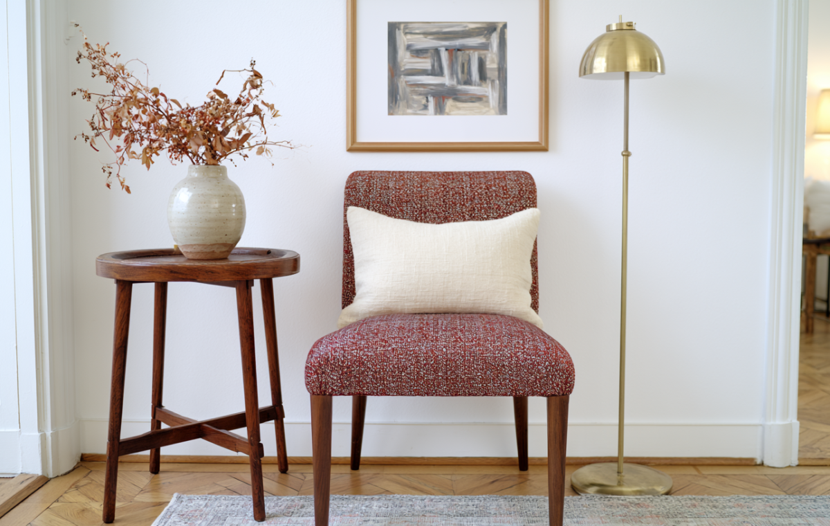 Accent chair styling with textured fabric, a wooden side table, and a brass floor lamp in a bright living room corner.