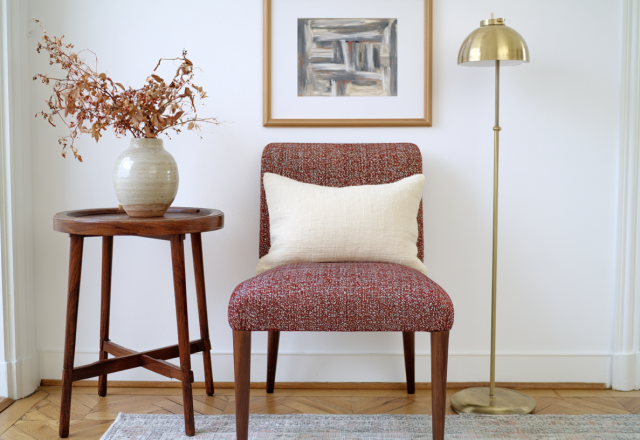 Accent chair styling with textured fabric, a wooden side table, and a brass floor lamp in a bright living room corner.
