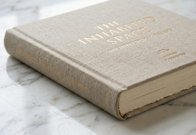 Close up of an architectural essay book with linen cover on a white marble surface.