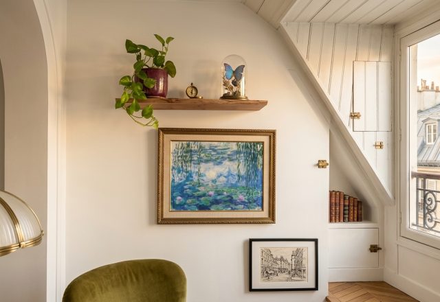 Cozy attic bedroom art display featuring a gilt-framed painting and floating shelf under a sloped ceiling.