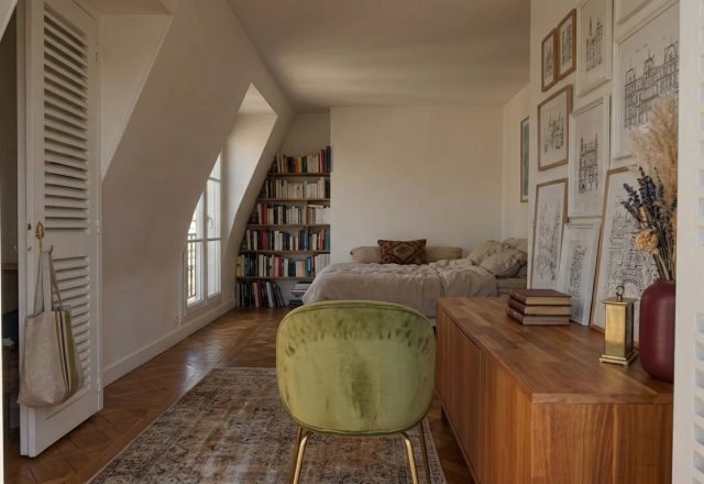 Cozy attic bedroom design featuring sloped ceilings, built-in bookshelf, and a green velvet chair.