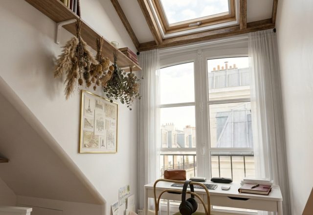 Bright attic home office with a white desk, sloped walls, and large windows bringing in natural light.