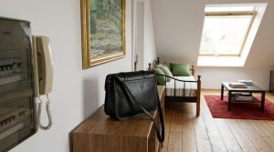 Black leather bag on a wooden console table in a bright attic living room with sloped ceilings and skylight.
