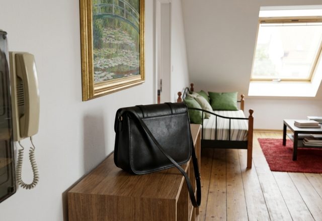 Black leather bag on a wooden console table in a bright attic living room with sloped ceilings and skylight.