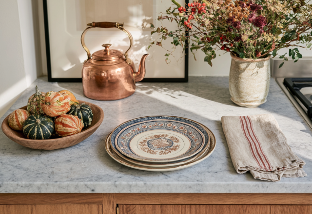 Cozy autumn kitchen styling with miniature gourds, a copper kettle, and dried flowers on marble countertops.