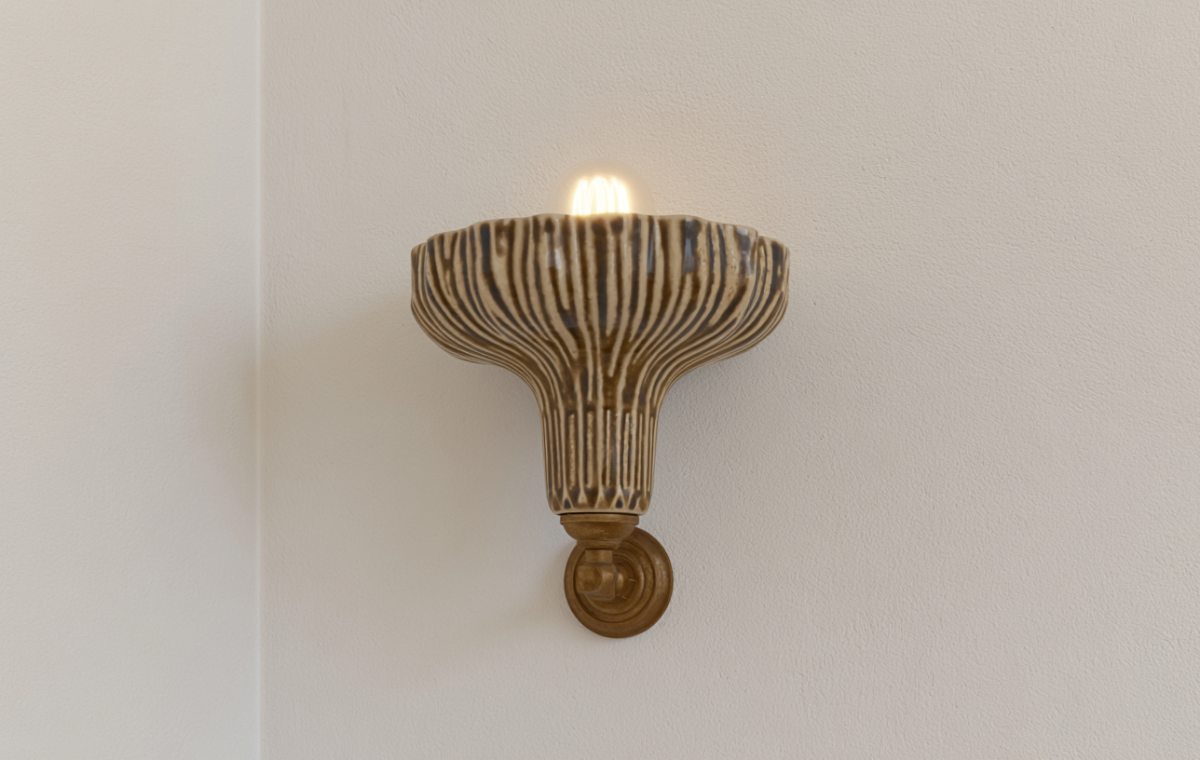 A ribbed ceramic wall sconce with a warm glowing bulb mounted on a neutral plaster wall.