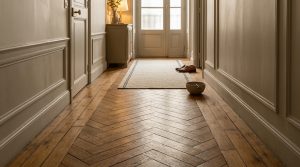 Hallway with chevron parquet flooring, straight border planks, and classic wall mouldings.