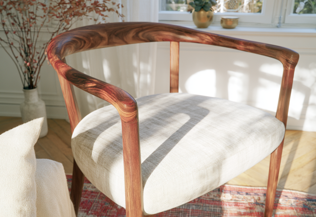 A sleek wooden armchair with a neutral upholstered seat sitting in a sunlit living room with herringbone floors.