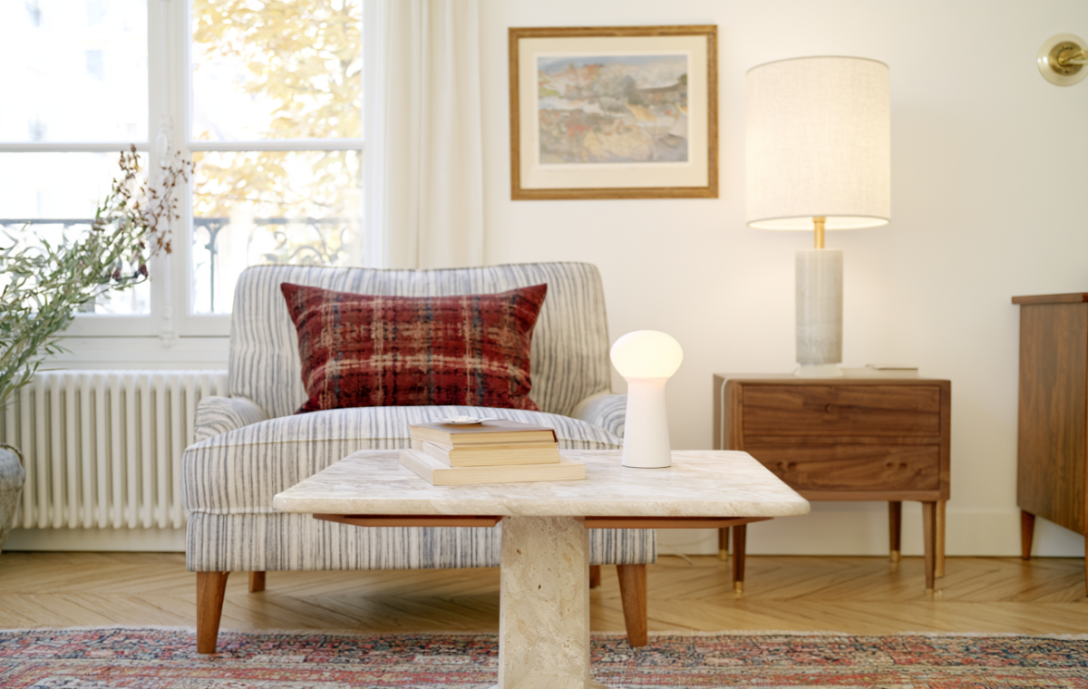 Cozy living room decor featuring a travertine coffee table, striped armchair, and warm table lamp.