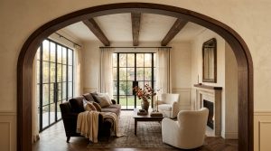 Transitional living room featuring dark wood ceiling beams, steel framed windows, and warm neutral walls.