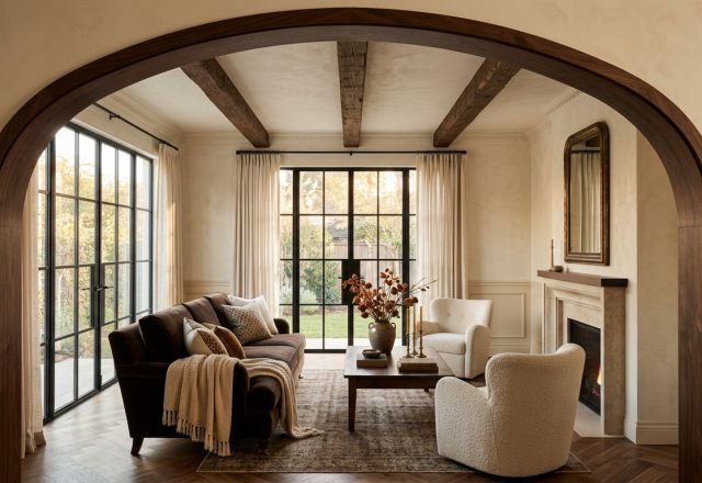 Transitional living room featuring dark wood ceiling beams, steel framed windows, and warm neutral walls.