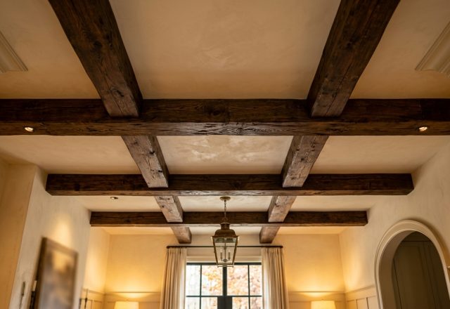 Living room ceiling featuring dark exposed wooden beams and a brass pendant light