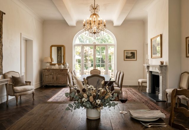 Elegant formal dining room featuring a crystal chandelier, herringbone wood floors, and a traditional fireplace.