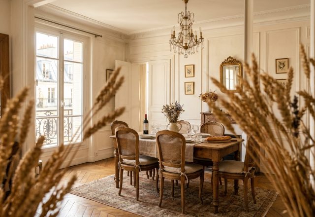 A bright French Country dining room featuring cane back chairs, parquet floors, and tall windows.