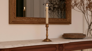 Vintage brass mantel candle holder on a marble and wood fireplace mantel with a gold framed mirror.