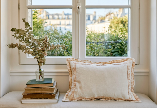Cozy window seat decor featuring a linen accent pillow, vintage books, and a glass vase with dried eucalyptus.