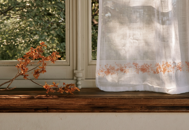 Minimalist window sill decor featuring a rustic dried branch on a wooden ledge next to a sheer curtain.
