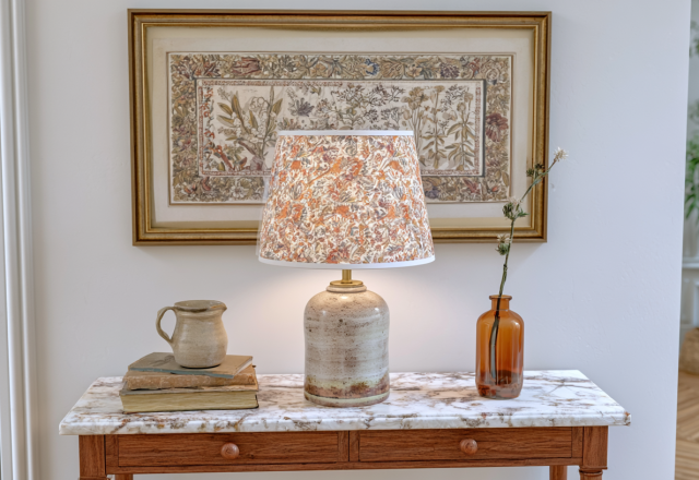 Styled entryway console table with marble top, vintage botanical art, and a patterned ceramic table lamp.