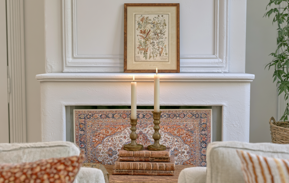 Fireplace mantel decor featuring antique brass candlesticks, vintage books, and a framed botanical illustration print.