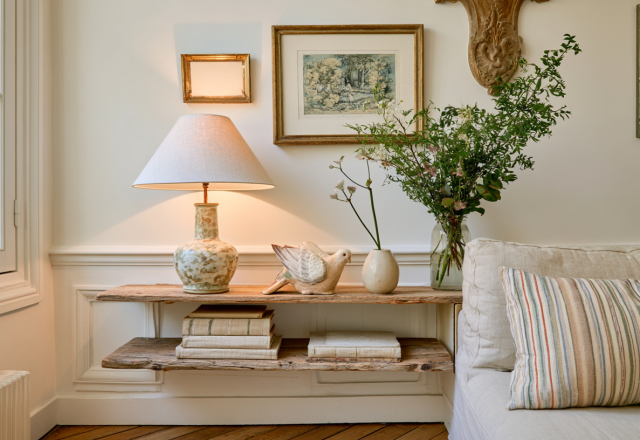 Floating wooden shelves styled with books, a table lamp, and greenery in a bright living room.
