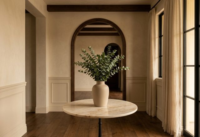 Sophisticated foyer styling ideas featuring a round marble table and eucalyptus in a minimalist neutral hallway.