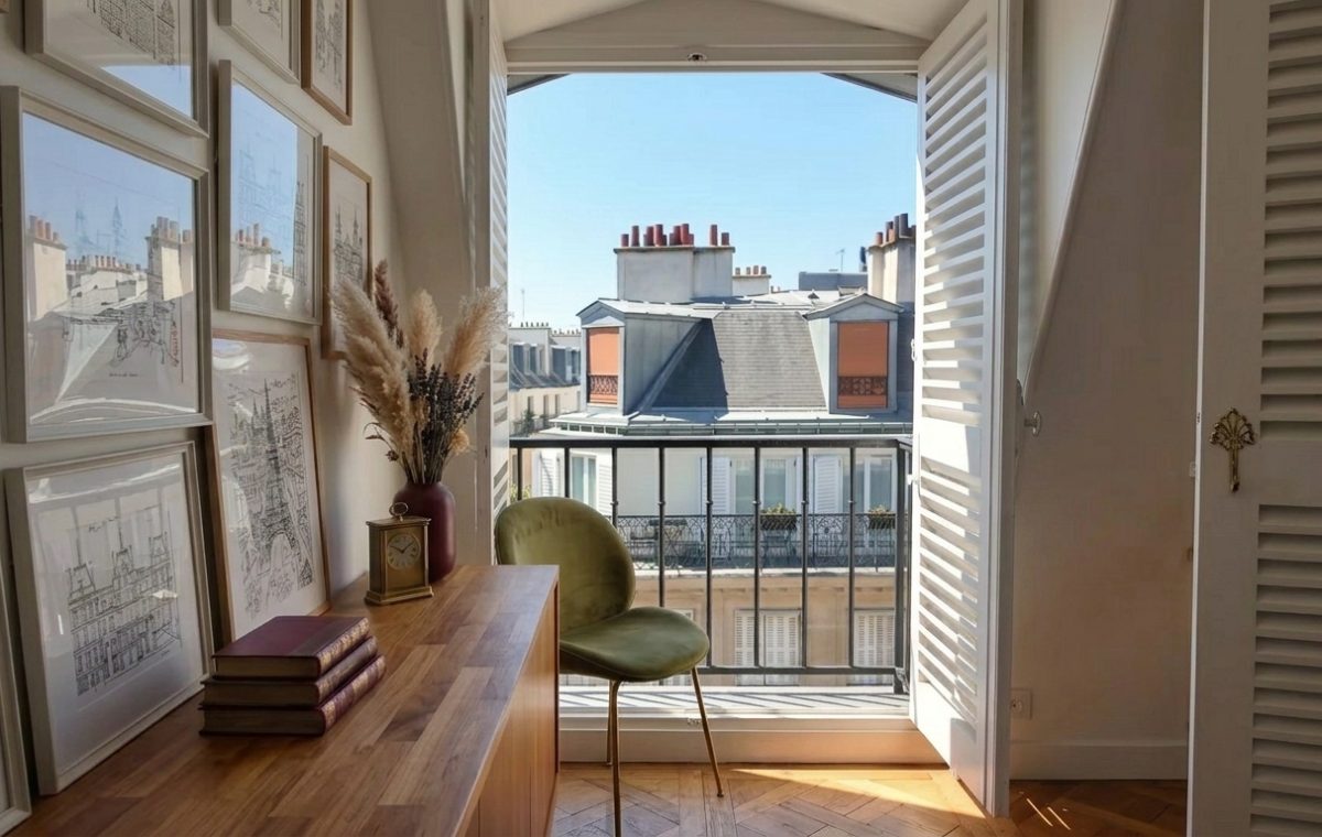 French apartment balcony decor featuring a green velvet chair and gallery wall next to open balcony doors.