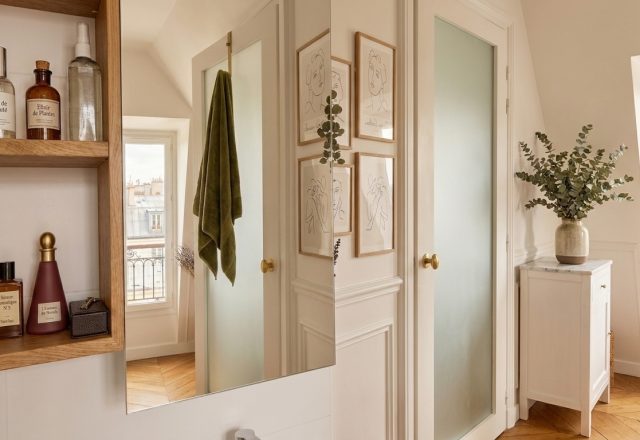 French apartment bathroom decor featuring open wooden shelves, apothecary bottles, and herringbone wood floors.