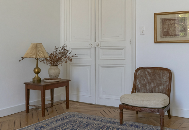 French country living room featuring a vintage side table, cane chair, and herringbone wood floors.