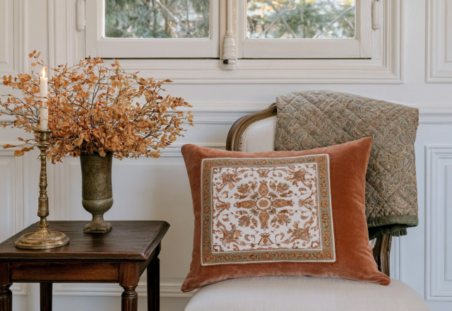 French Country living room decor featuring an antique wood side table, velvet pillow, and dried botanicals