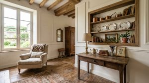 Bright French Country living room featuring rustic wood beams, a neutral armchair, and vintage wooden console table.