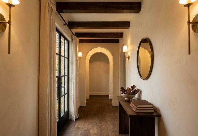 Elegant hallway lighting ideas featuring brass wall sconces, exposed timber beams, and a narrow wood console table.