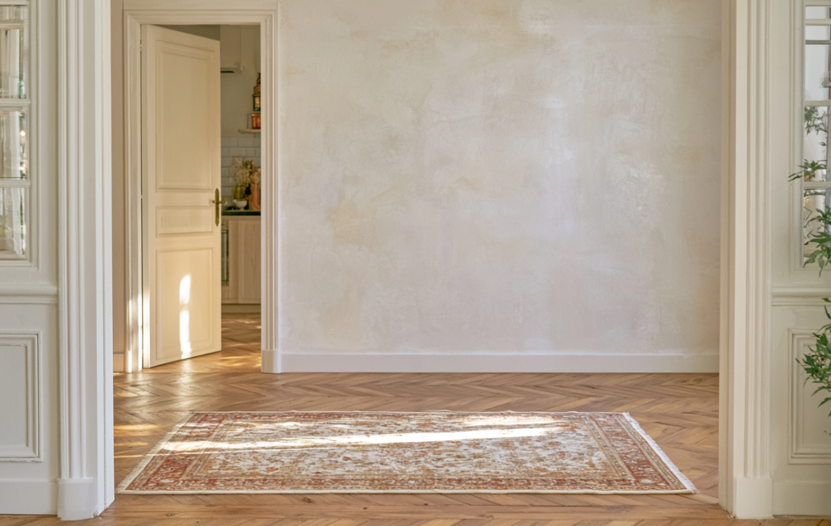 Hardwood flooring ideas featuring herringbone wood floors and an antique rug in a sunlit historic home interior