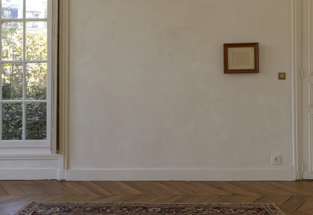 Hardwood flooring maintenance in a bright room with classic parquet and tall windows showing natural daylight reflection.