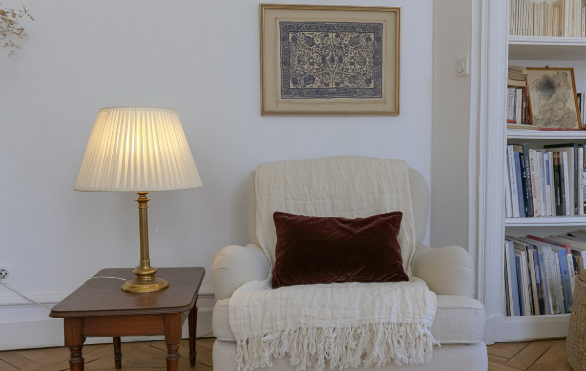 A cozy reading corner setup featuring an armchair, brass table lamp, and built-in bookshelves.