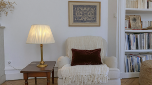 A cozy reading corner setup featuring an armchair, brass table lamp, and built-in bookshelves.