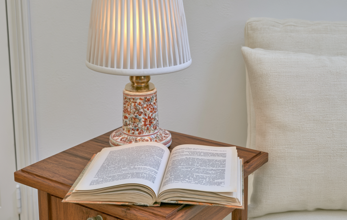 Cozy bedside reading nook featuring an open book and floral ceramic lamp on a wooden nightstand
