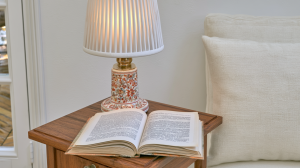 Cozy bedside reading nook featuring an open book and floral ceramic lamp on a wooden nightstand