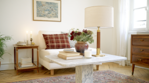 A styled marble coffee table with a brass lamp and floral vase in a neutral living room.