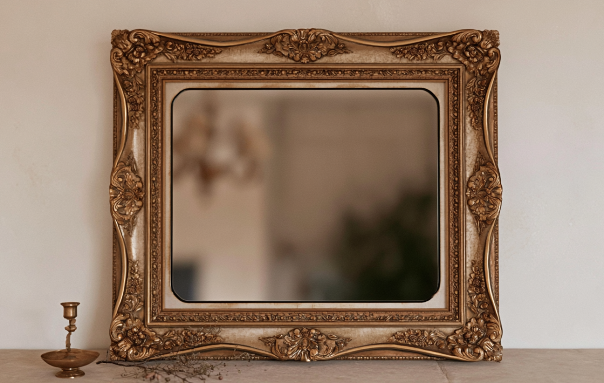 Ornate antique gold mirror mounted above a console with a brass candlestick.
