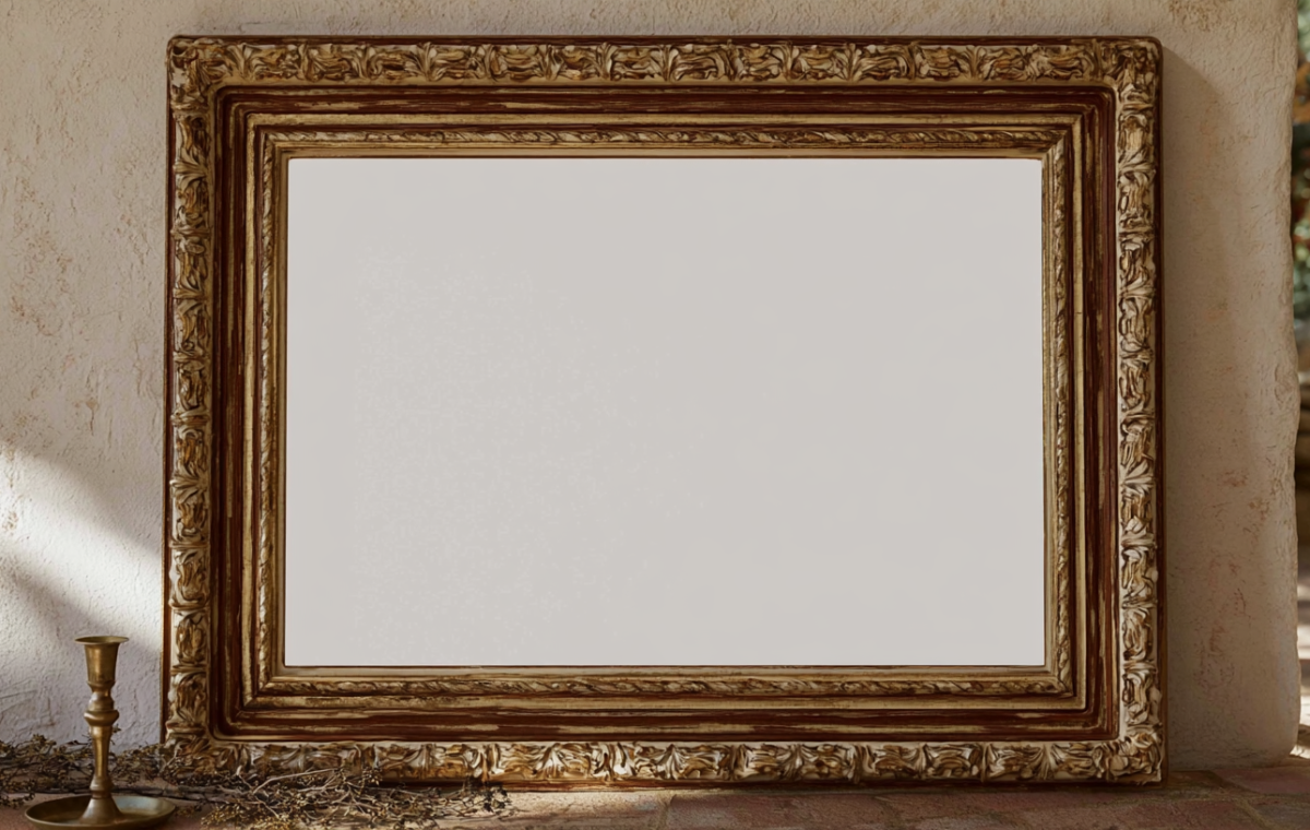 An ornate antique picture frame leaning against a textured rustic wall with a brass candleholder