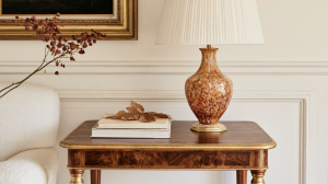 An antique side table styled with a ceramic lamp, books, and dried botanicals in a classic living room.