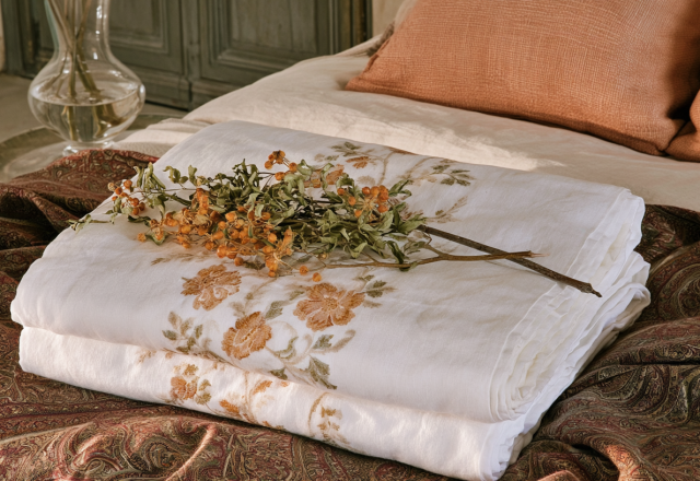 Layered linen bedding featuring botanical prints and terracotta pillows on a rustic bed
