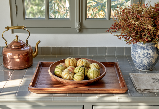 Kitchen seasonal decor featuring a wooden tray with small gourds, a copper kettle, and dried botanicals on a tiled countertop.