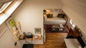 Cozy loft living room featuring a daybed under sloped ceilings and wooden flooring