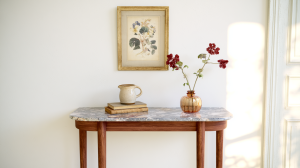 Console table styling with marble top, framed botanical art, and amber glass vase in a bright entryway.