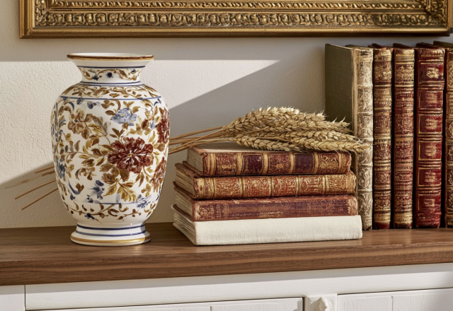 Vintage shelf styling featuring antique leather-bound books and a floral ceramic vase on a dark wood console table.