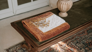 Antique wooden bench styling with a terracotta velvet blanket and a ceramic vase in an entryway